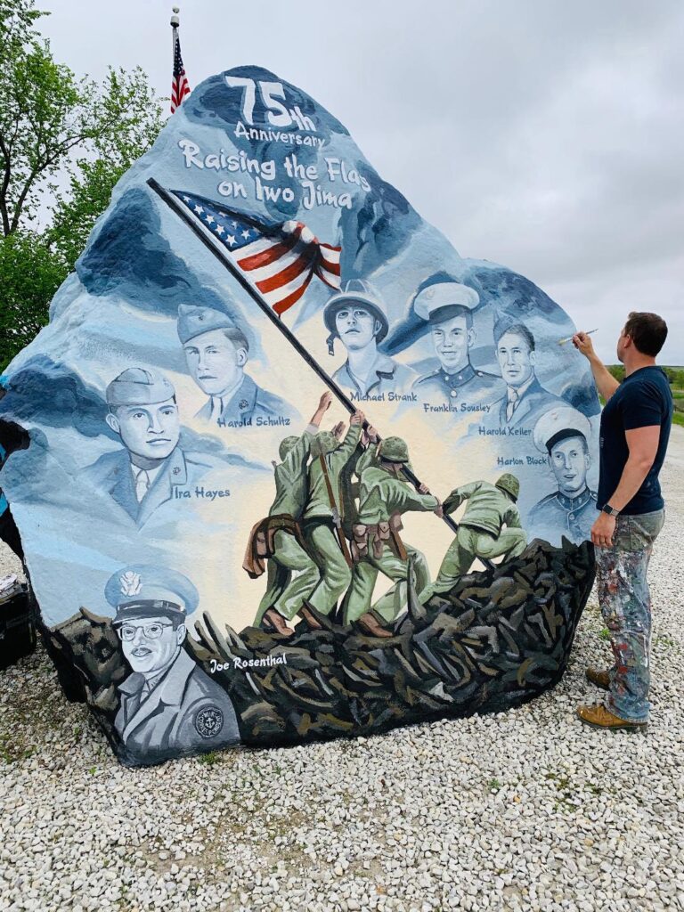 Large rock painted with soldiers and American flag with man on the side painting