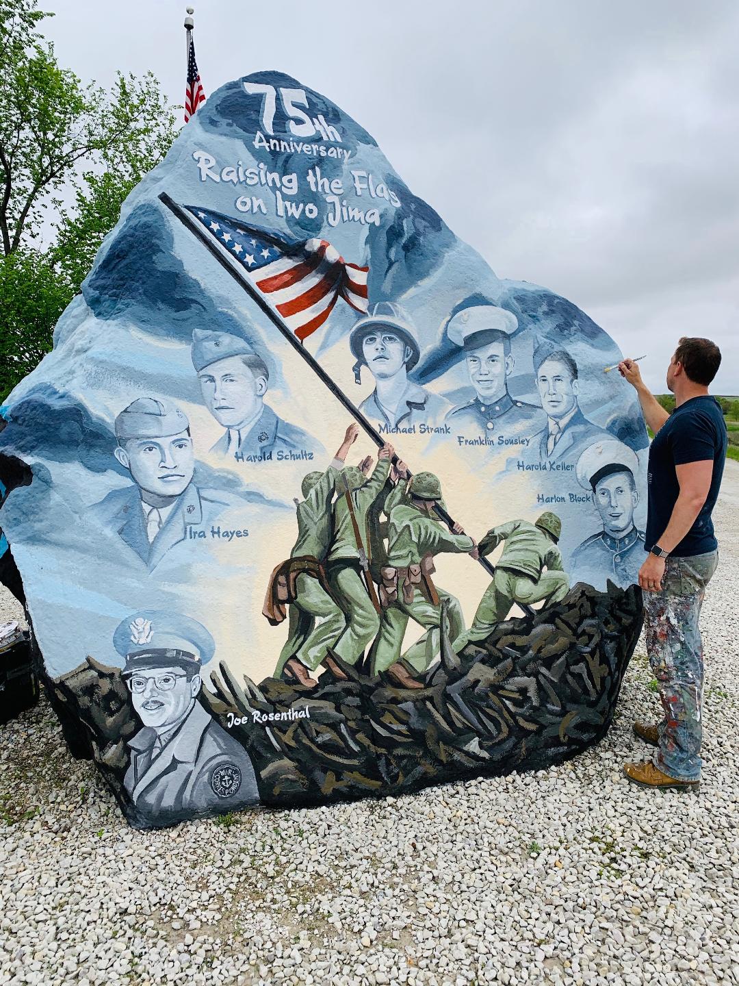 Large rock painted with soldiers and American flag with man on the side painting