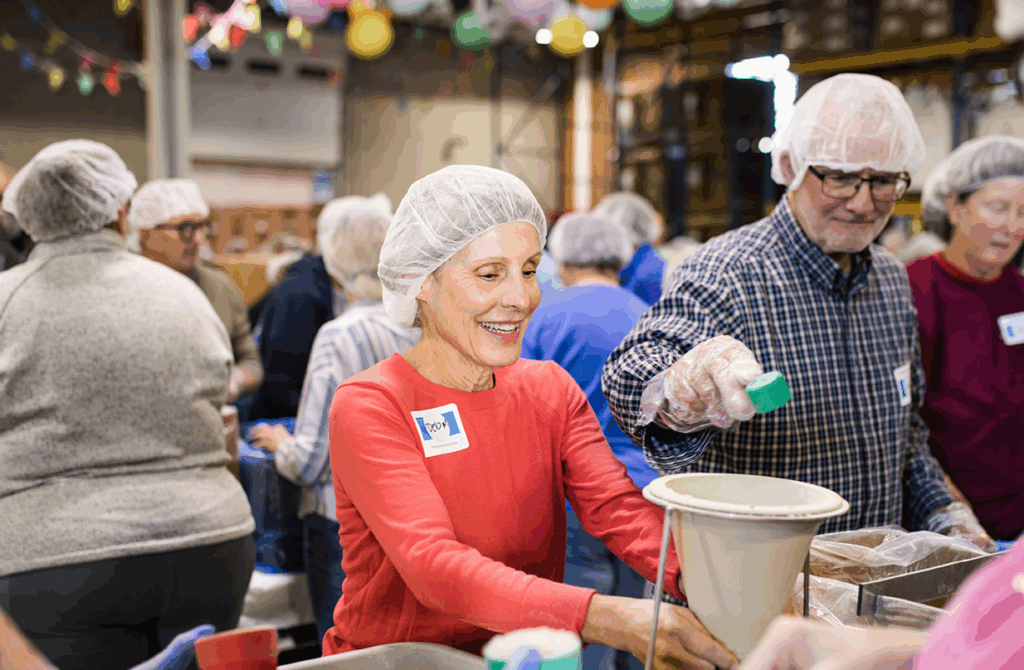 Group of people preparing meals in an assembly line fashion.