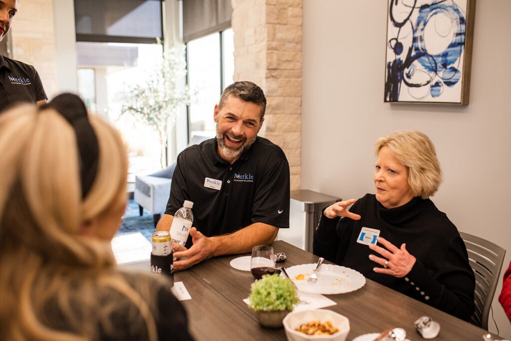 Man speaking to two women. All laughing.