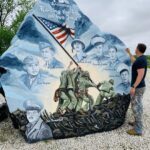 Large rock painted with soldiers and American flag with man on the side painting