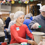 LL_Visual_MFTH Group of people preparing meals in an assembly line fashion.