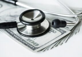 Closeup of cash and a stethoscope healthcare and expenses concept